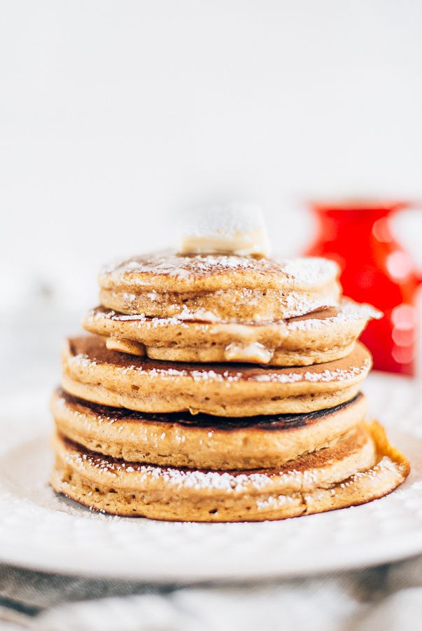 white plate and white background with a stack of pumpkin pancakes