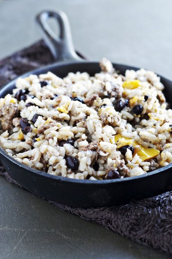 Cajun Dirty Rice plated in a cast iron skillet with a light grey backdrop and purple napkin