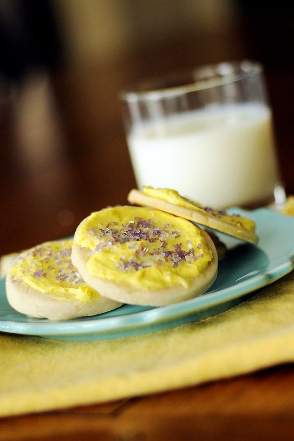 plate of yellow frosted sugar cookies and a glass of milk