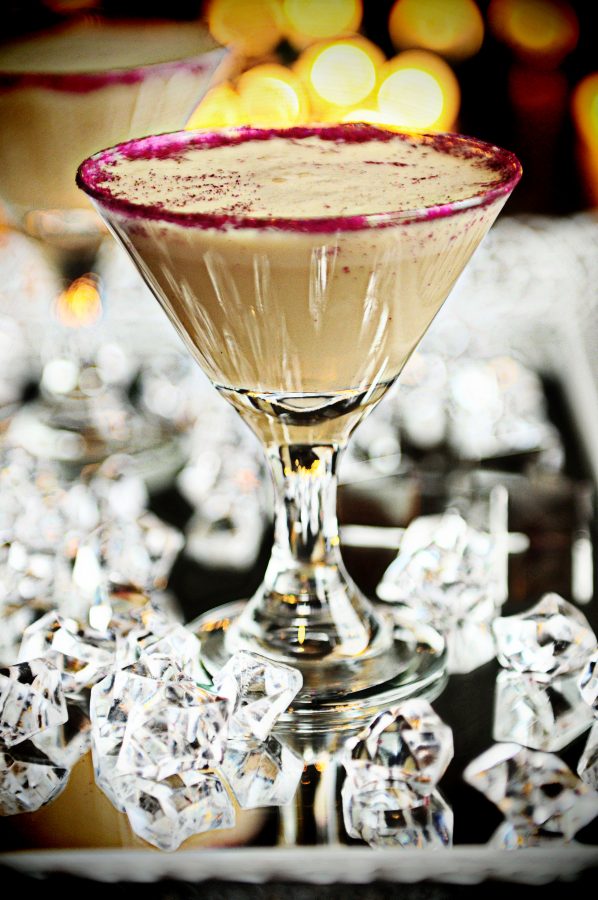A martini glass on a mirrored surface filled with a creamy chocolate mudslide cocktail