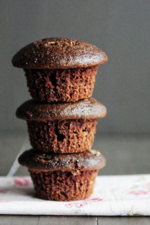 stack of 3 chocolate muffins with a brown backdrop