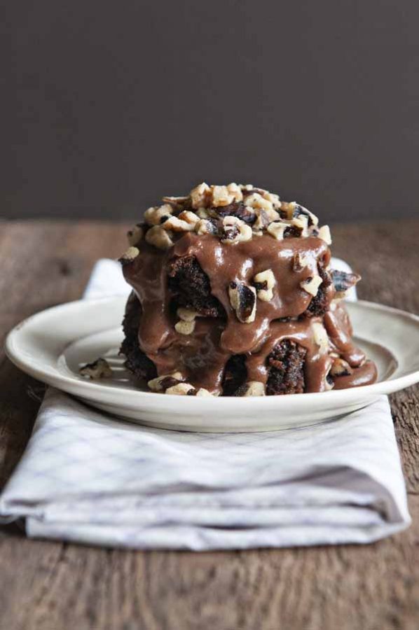 Decadent Frosted Brownies on a white plate with a brown backdrop.