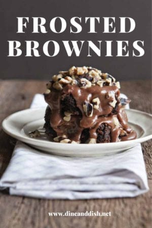 plate of brownies with rich and creamy frosting poured over the top on a brown backdrop