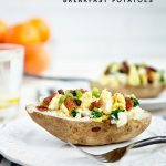 Twice Baked Breakfast Potatoes with eggs, bacon and spinach served on a white plate with white brick background