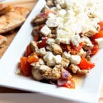 Greek Feta Chicken Appetizer on a white plate with tomatoes and red onions