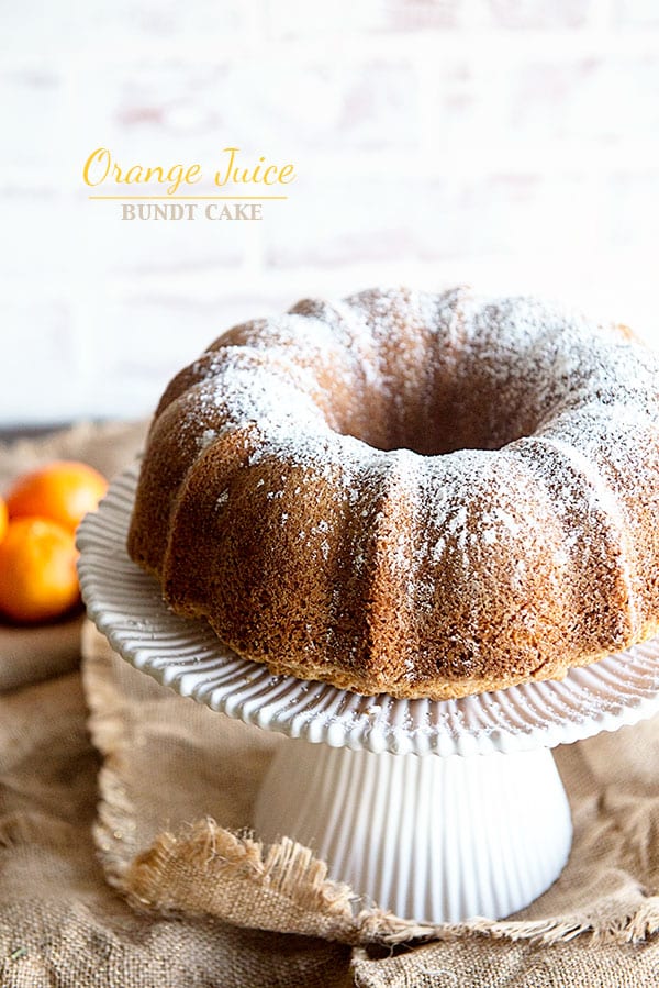 Bundt Cake on a white cake stand with white background and oranges