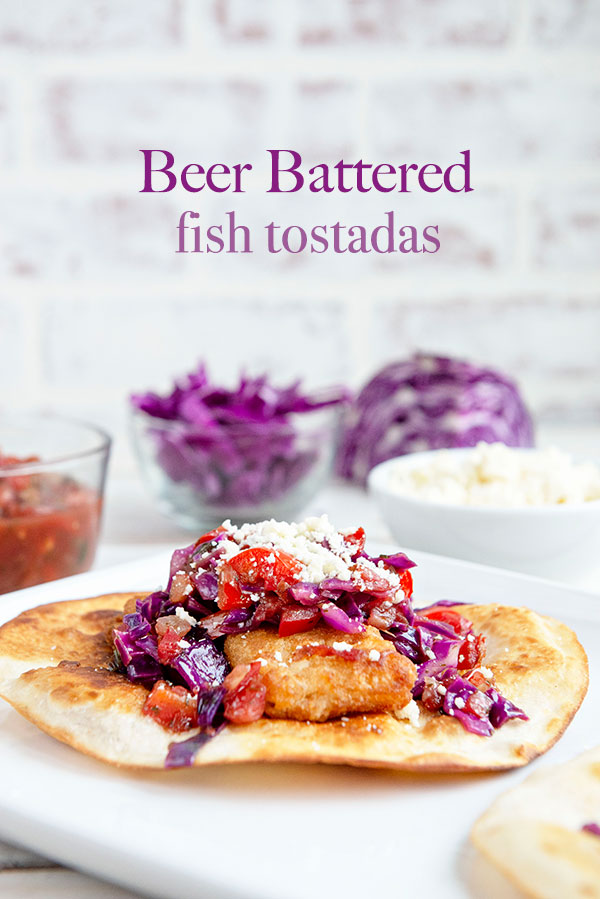 White background with a tostada featuring beer battered fish, cojita cheese and purple cabbage