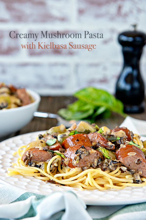 white plate with creamy mushroom pasta and kielbasa sausage