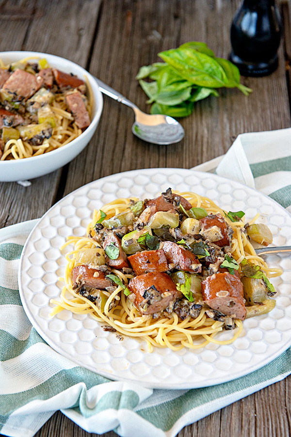 White plate with kielbasa sausage and creamy mushroom pasta