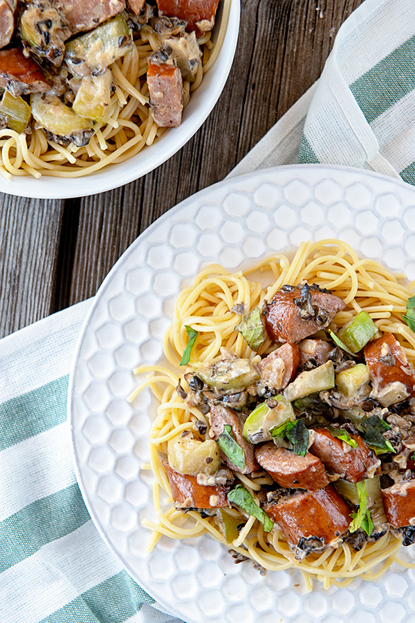 White plate loaded with spaghetti and a creamy mushroom sauce