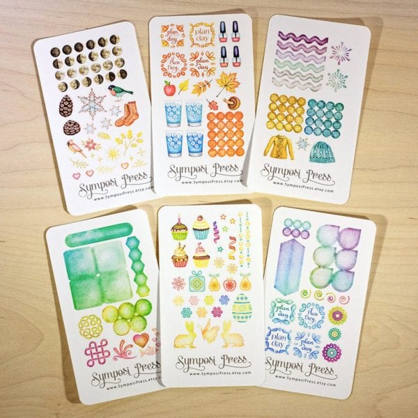 6 sticker sheets on wood background from Symposi Press Etsy store