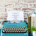 Typewriter sitting on a suitcase with books and a plant nearby and a list of favorite books read in 2019
