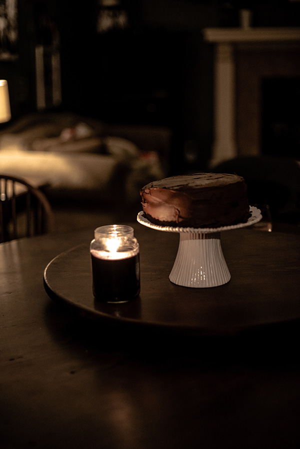 Dark Chocolate Cake on a white cake stand and wood table