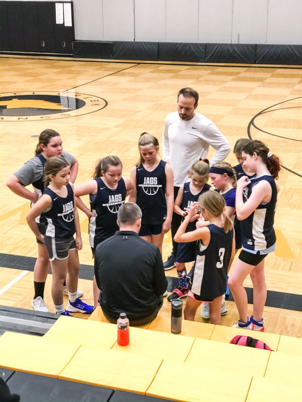 Girls Basketball Team Huddled Around their Coach