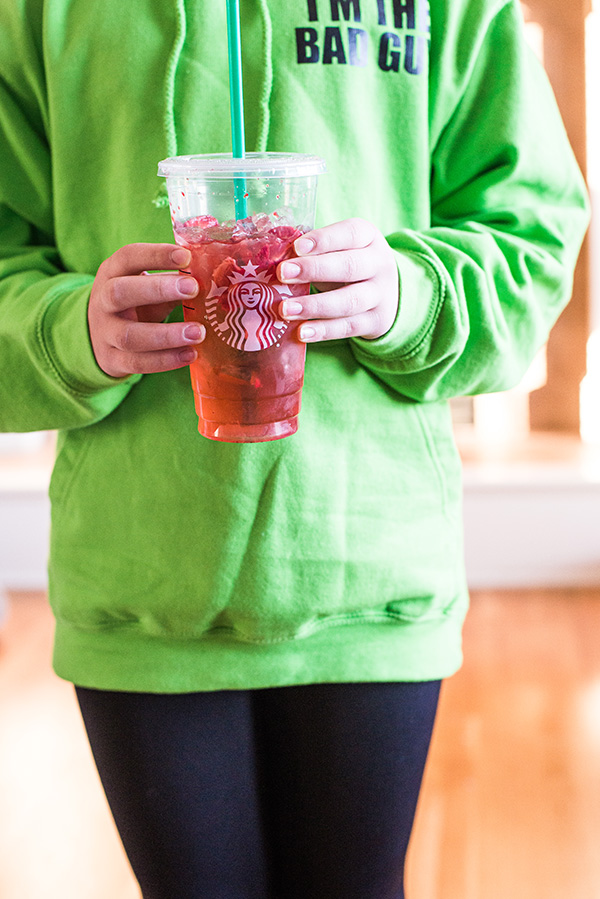 Girl with green shirt holding a Starbucks Strawberry Refresher