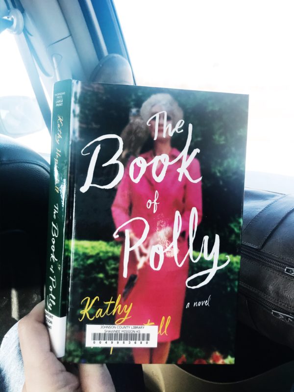 Hand holding the Book of Polly in a car