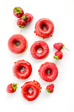 white background with red strawberry doughnuts and strawberries