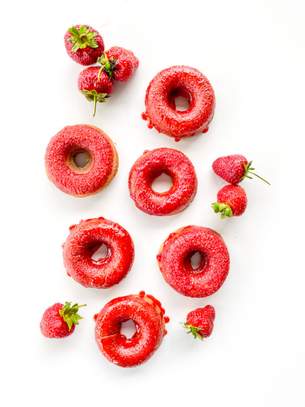 white background with red strawberry doughnuts and strawberries