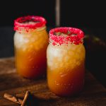 Image is of 2 mason jars on a wood background filler with a fireball cider cocktail