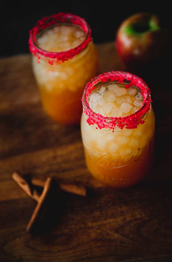 Image shows 2 mason jars filled with ice and an apple cider cocktail