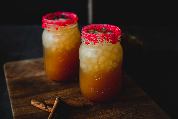 Image is of 2 mason jar fireball cocktails on a wood backdrop